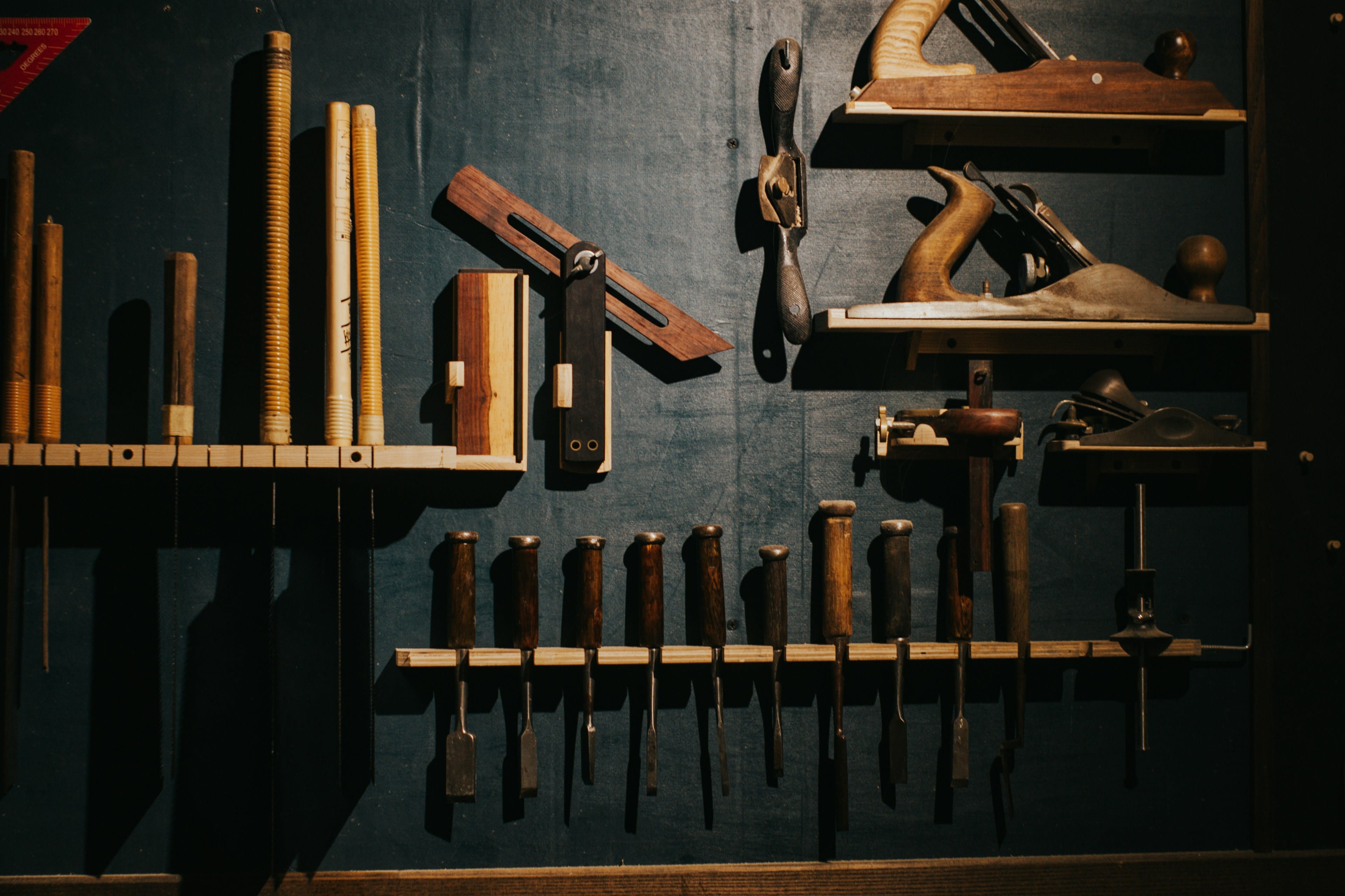 Outils d’atelier en bois et métal soigneusement rangés sur un mur sombre