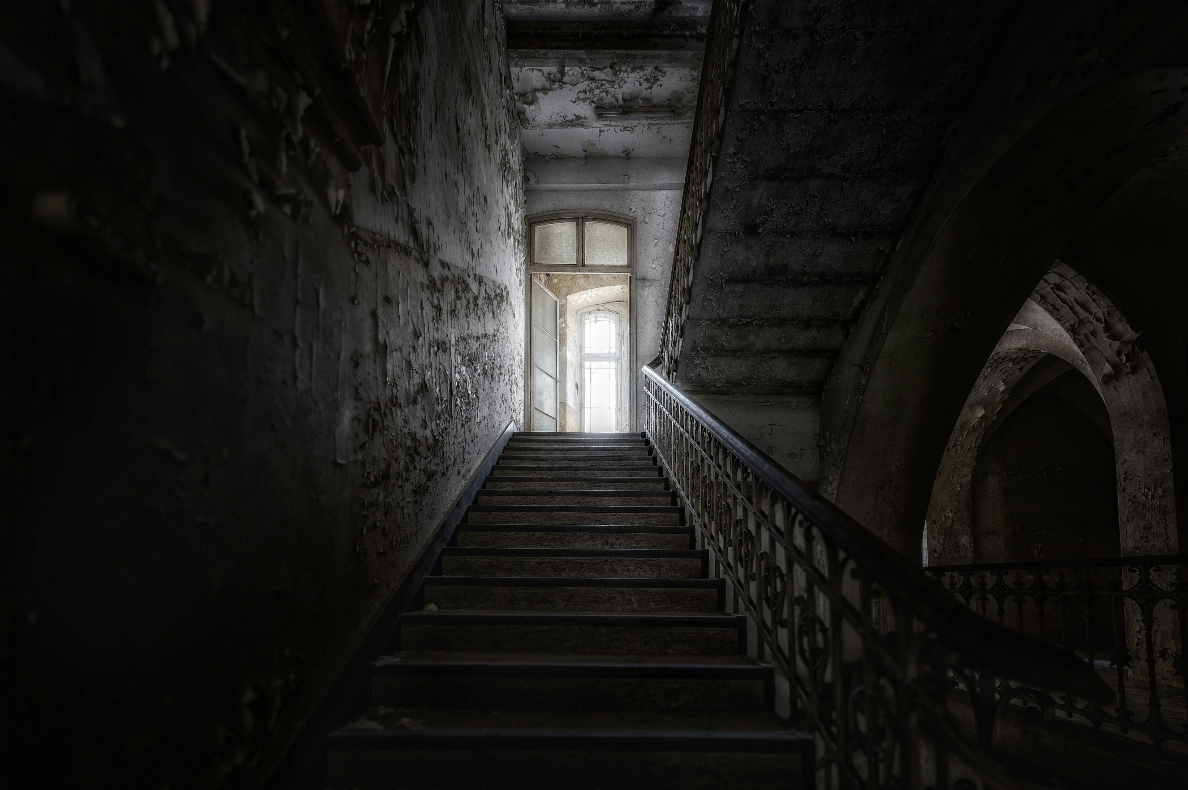 Escalier de pierre montant vers une porte baignée de lumière