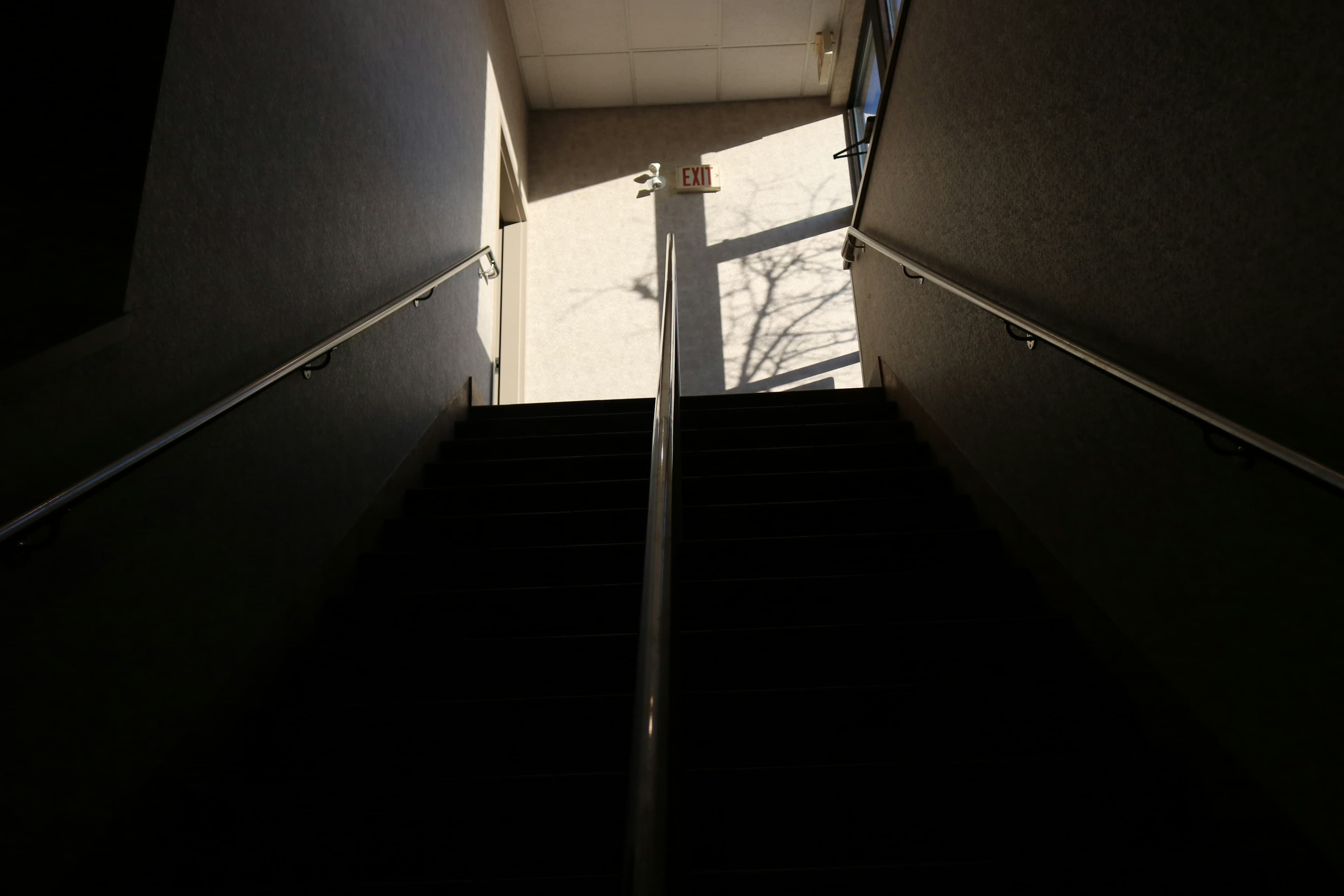 Escalier montant vers une porte baignée de lumière